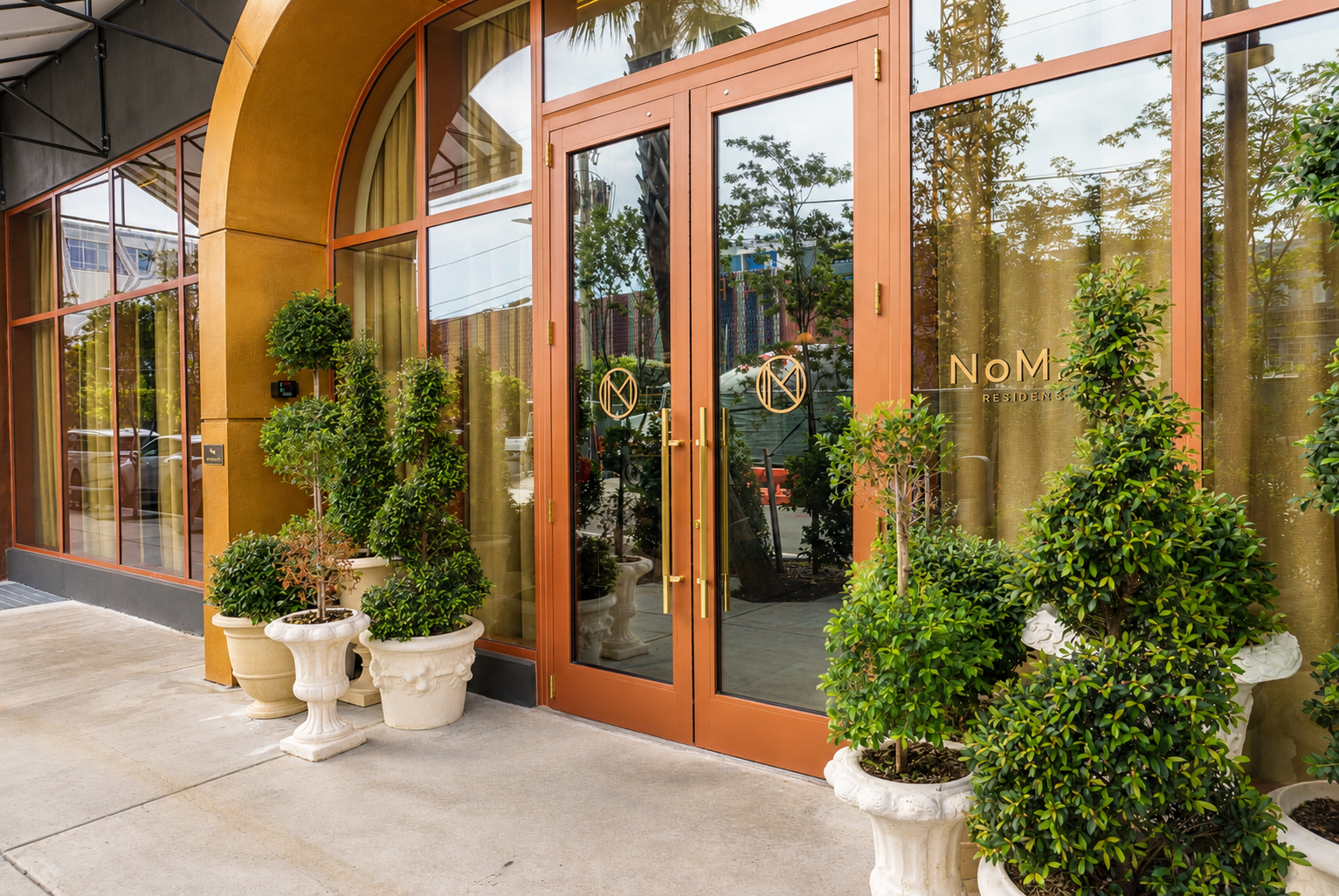 NoMad Residences entrance — arched doors, gold hardware, topiaries