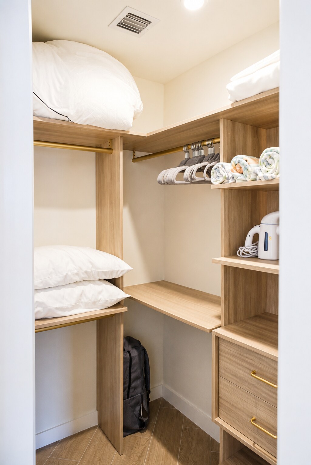 Bedroom closet with folded bedding, hangers, and built-in shelving
