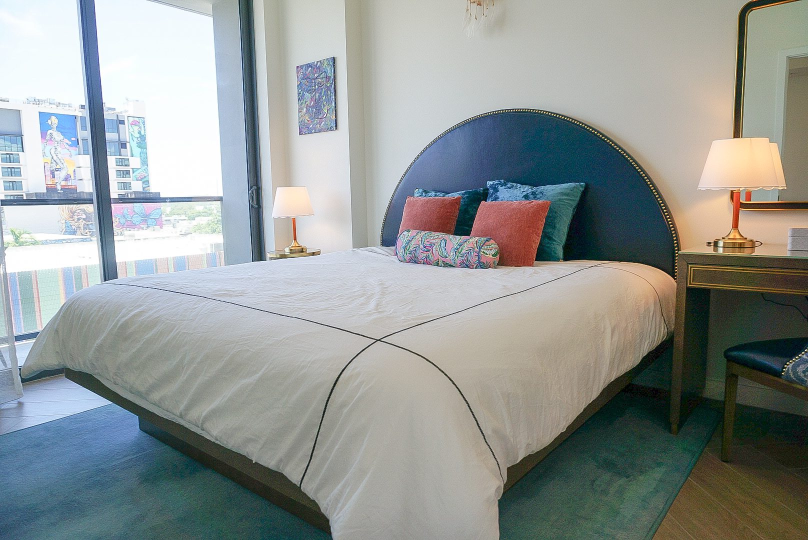 King bed — navy arched headboard, velvet pillows, Wynwood mural view