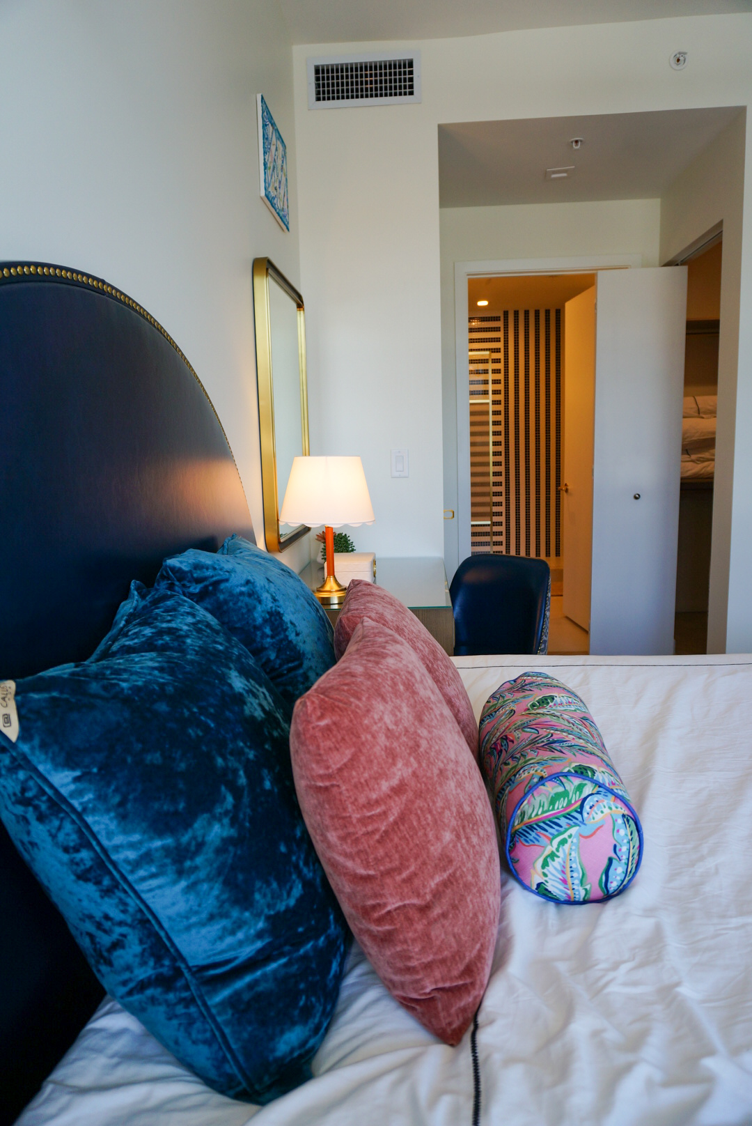 Bedroom pillows — teal and rose velvet, open bathroom door