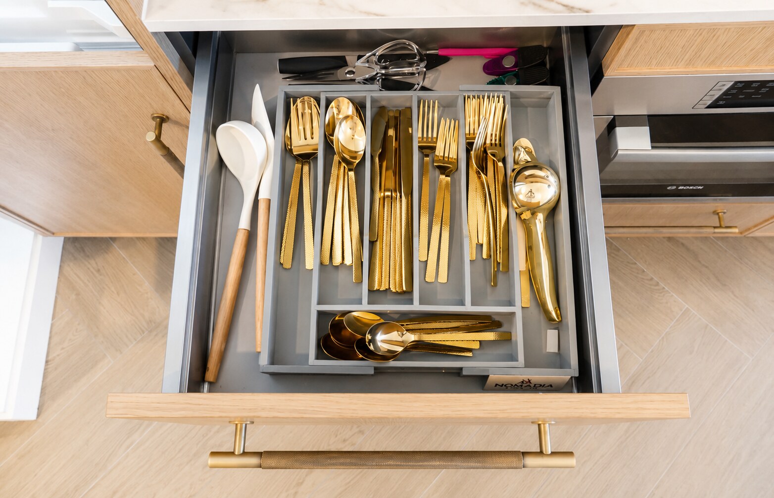 Open kitchen drawer with organized gold flatware