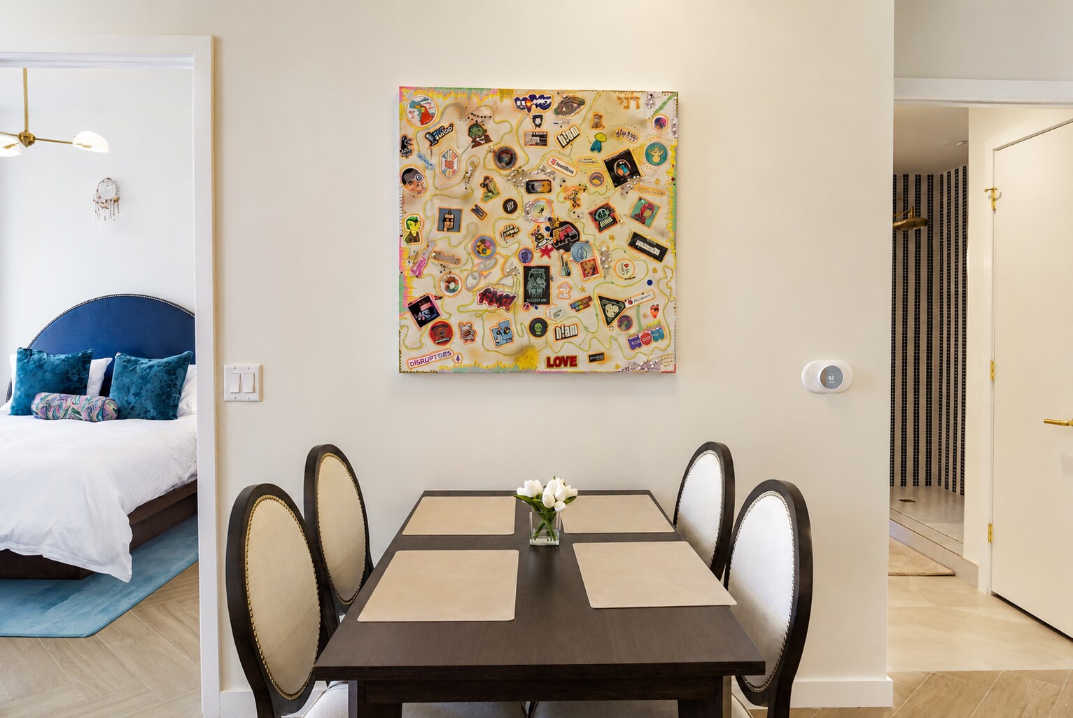 Dining area with colorful wall artwork, table, and view into bedroom